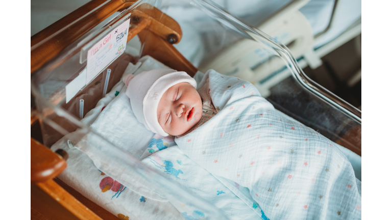 Newborn baby girl sleeps in incubator in hospital room