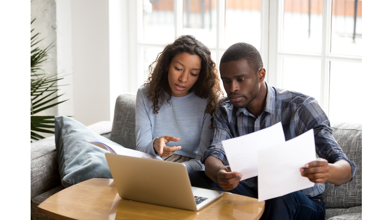 Serious African American couple discussing paper documents