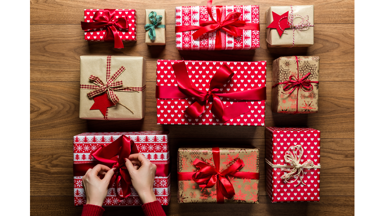 Cropped Hands Of Woman Arranging Christmas Presents On Hardwood Floor