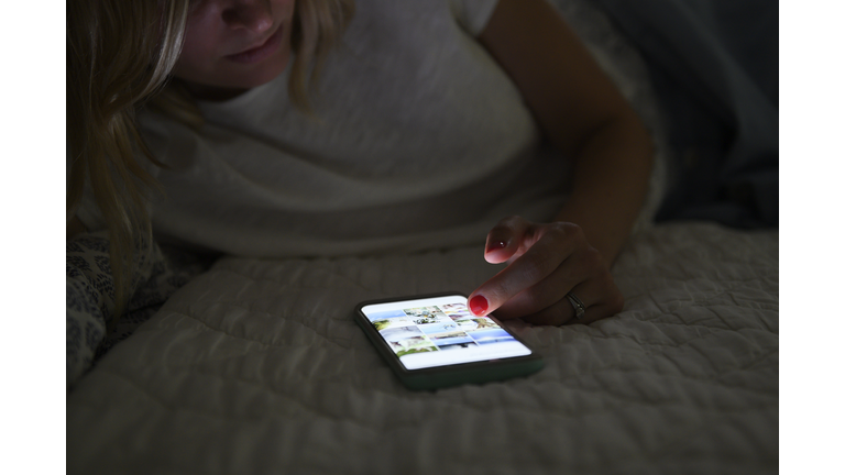 Woman scrolling through social media on smart phone at night