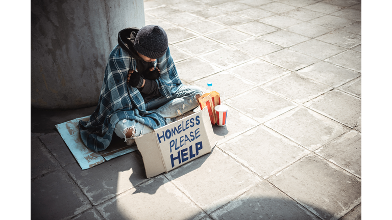 One man, young homeless sitting on the street and begging.