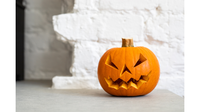 Halloween Pumpkin Lantern in front of a white brick wall