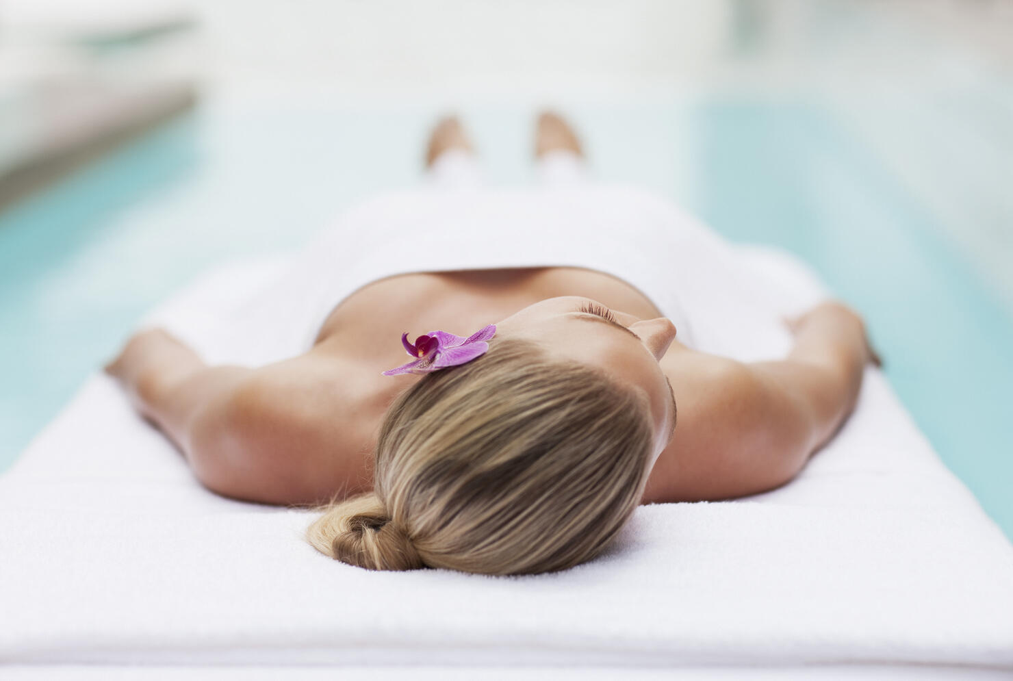 Woman laying on massage table at poolside