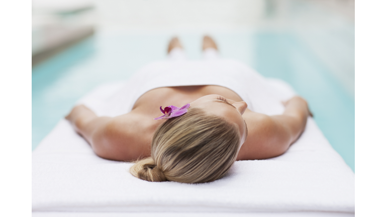Woman laying on massage table at poolside