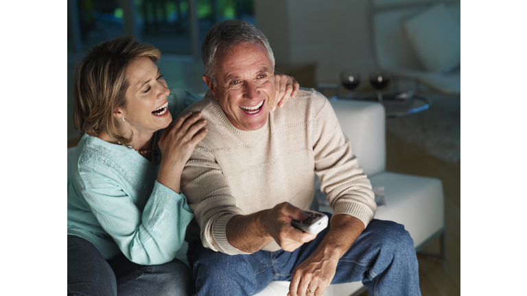 Couple in living room watching television and laughing