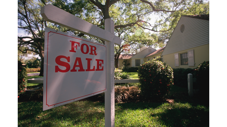 For sale sign hanging in front of house