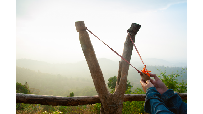 Cropped Hands Holding Slingshot Against Mountains