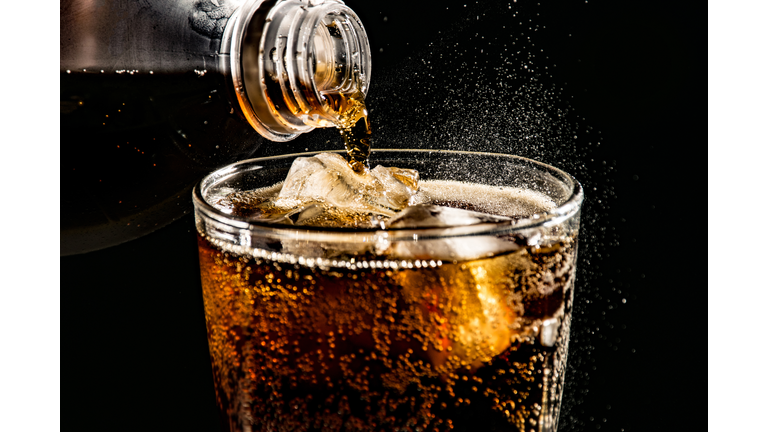Close-Up Of Drink Pouring In Drinking Glass Against Black Background