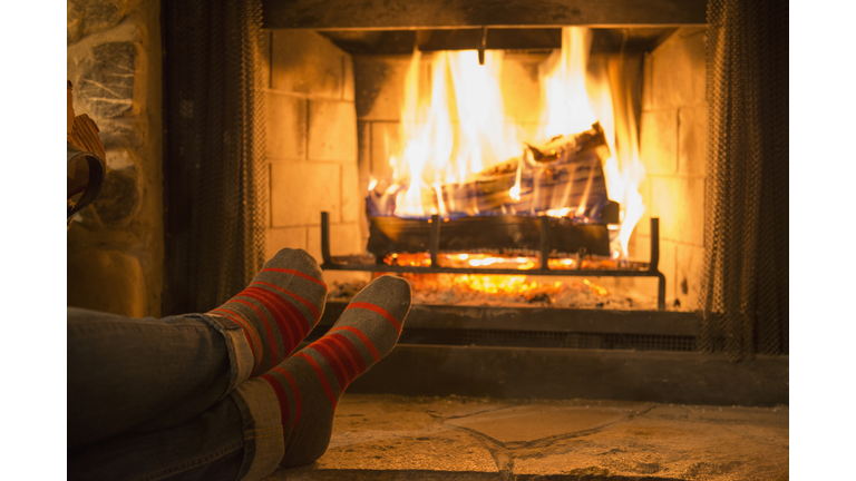 Caucasian woman warming feet near fireplace