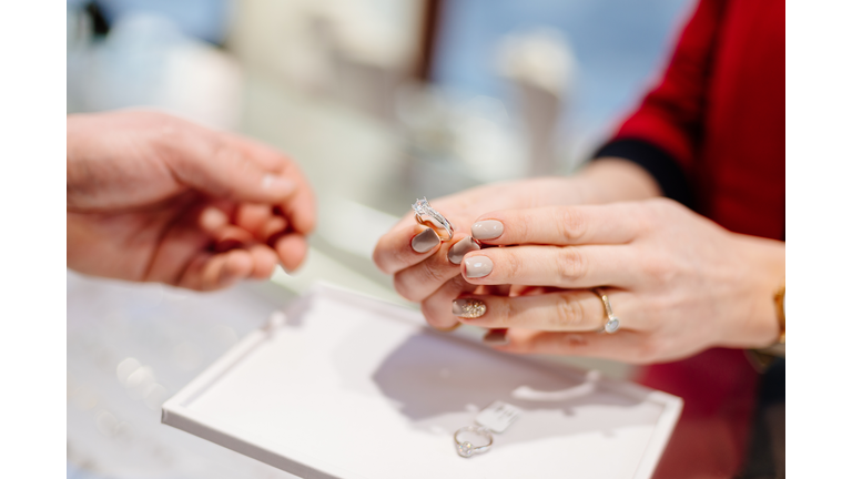 Female seller in a luxury jewelry store presents a ring.