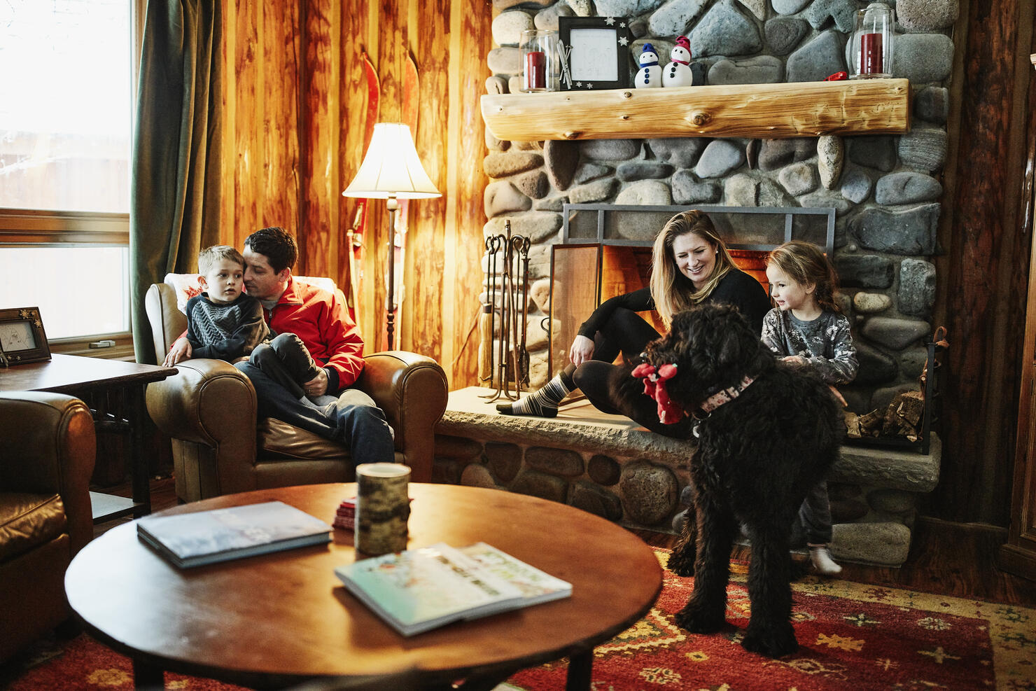 Family sitting by fireplace in winter cabin