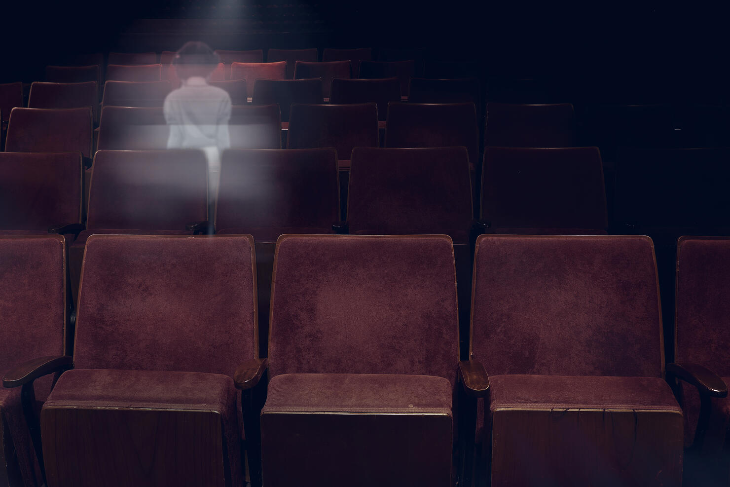 transparent ghost little girl appears between vintage seat in movie theater, horror film, halloween horror concept.
