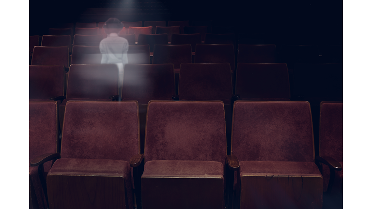 transparent ghost little girl appears between vintage seat in movie theater, horror film, halloween horror concept.
