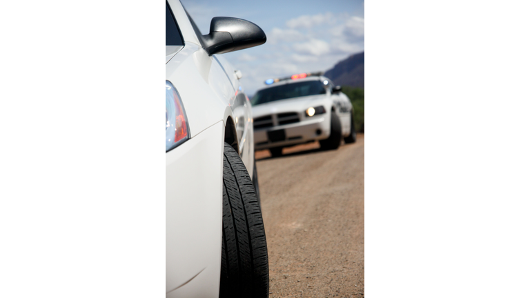 Police car stopping a dodge white car in front