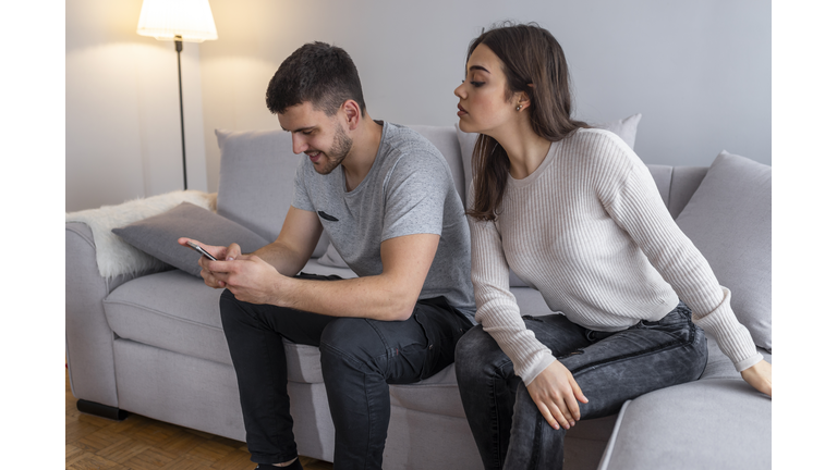 Jealous suspicious mad wife arguing with obsessed husband holding phone texting cheating on cellphone