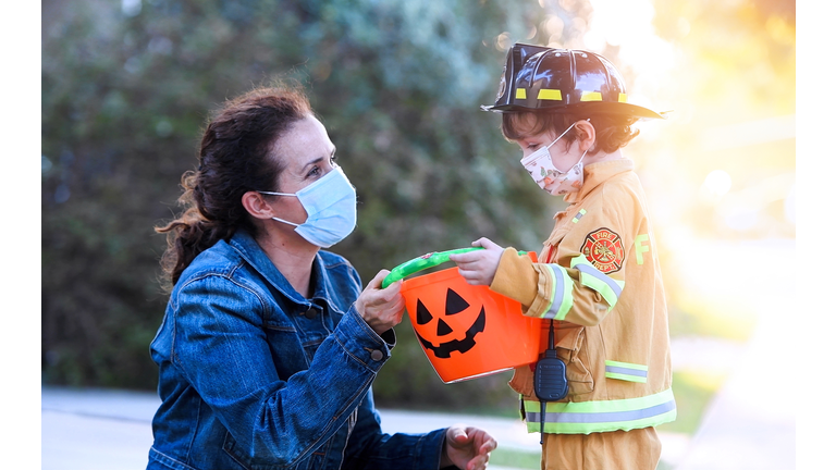 Mature woman and a child boy wearing protective face masks before going to ask trick or treat halloween