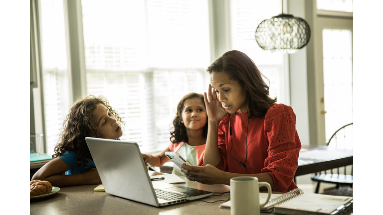 Mother working from home with children in background