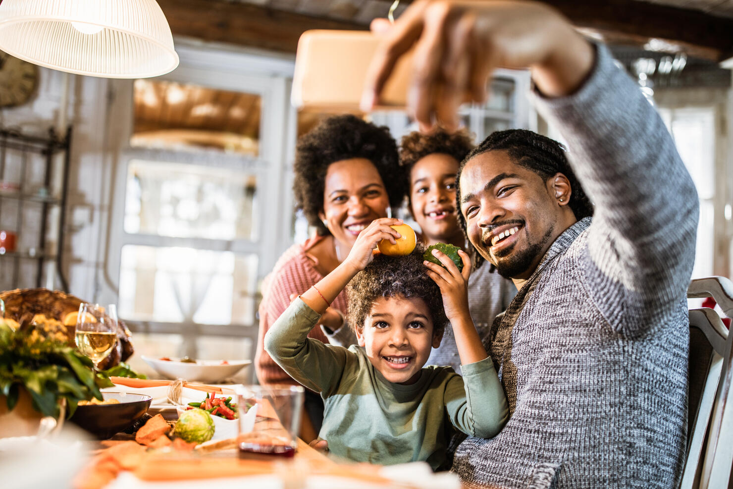 Happy black family taking a selfie with cell phone in dining room.