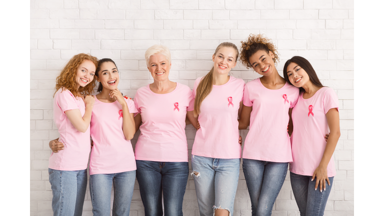 Multiethnic Women In Breast Cancer T-Shirts Hugging Over White Wall