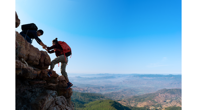 Asia couple hiking help each other in mountains view