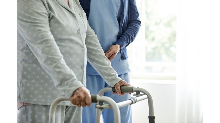 Nurse supporting disabled elderly woman in walking