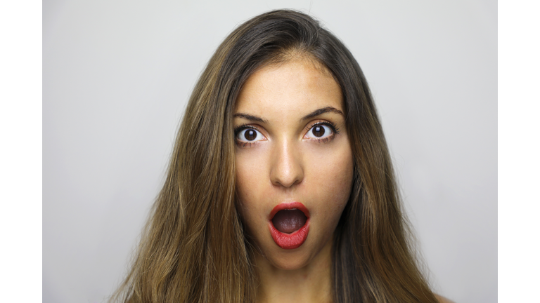 Close-Up Portrait Of Shocked Young Woman Against Gray Background