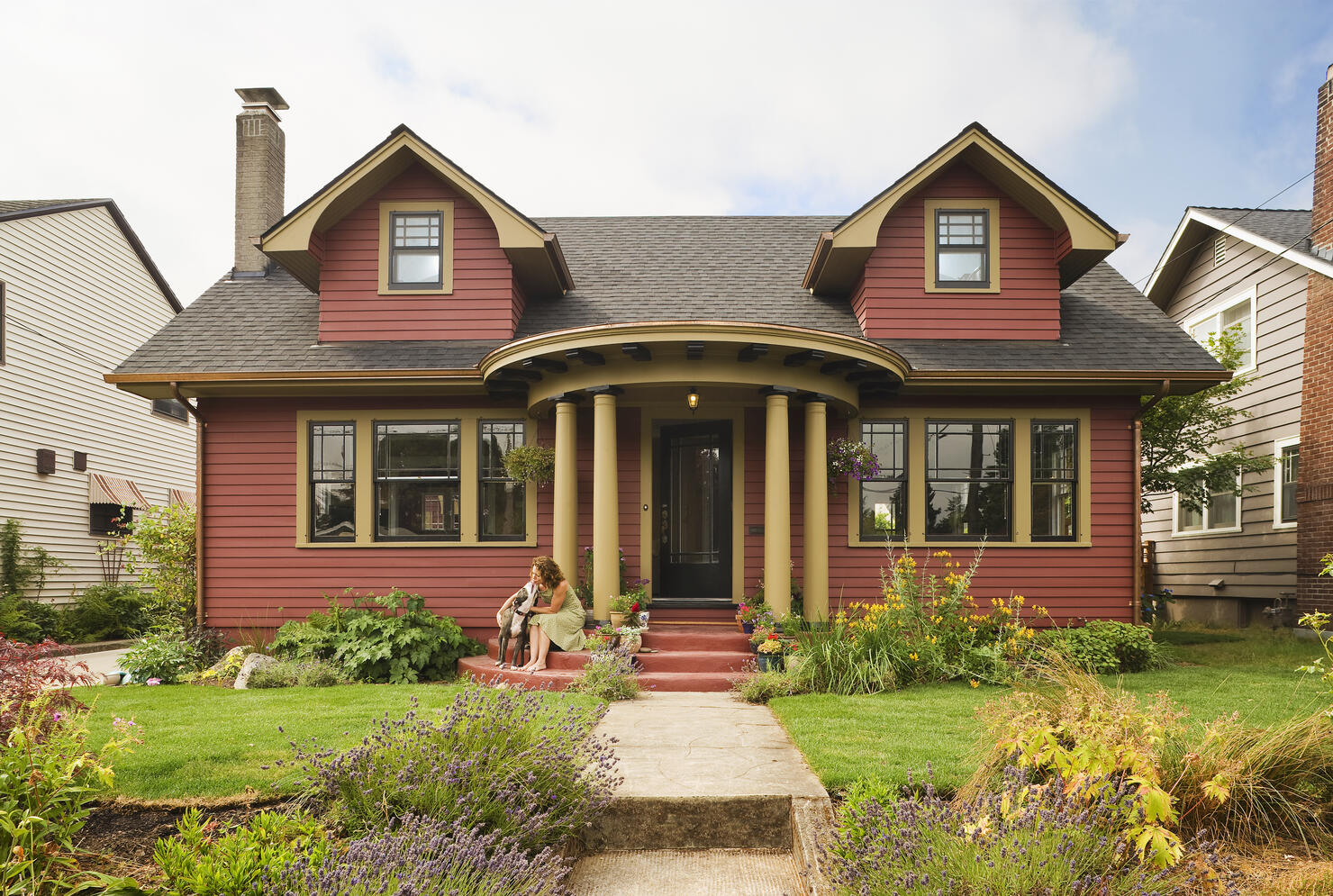 Woman & dog sitting on the porch of a quaint house