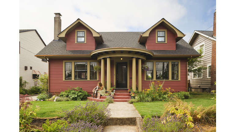 Woman & dog sitting on the porch of a quaint house