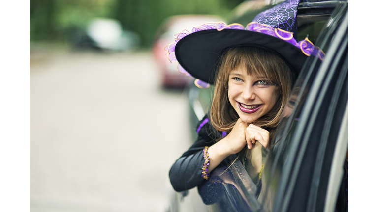 Little halloween witch smiling out of the car