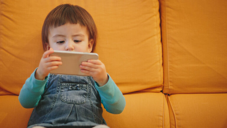 Toddler girl using a smartphone on couch