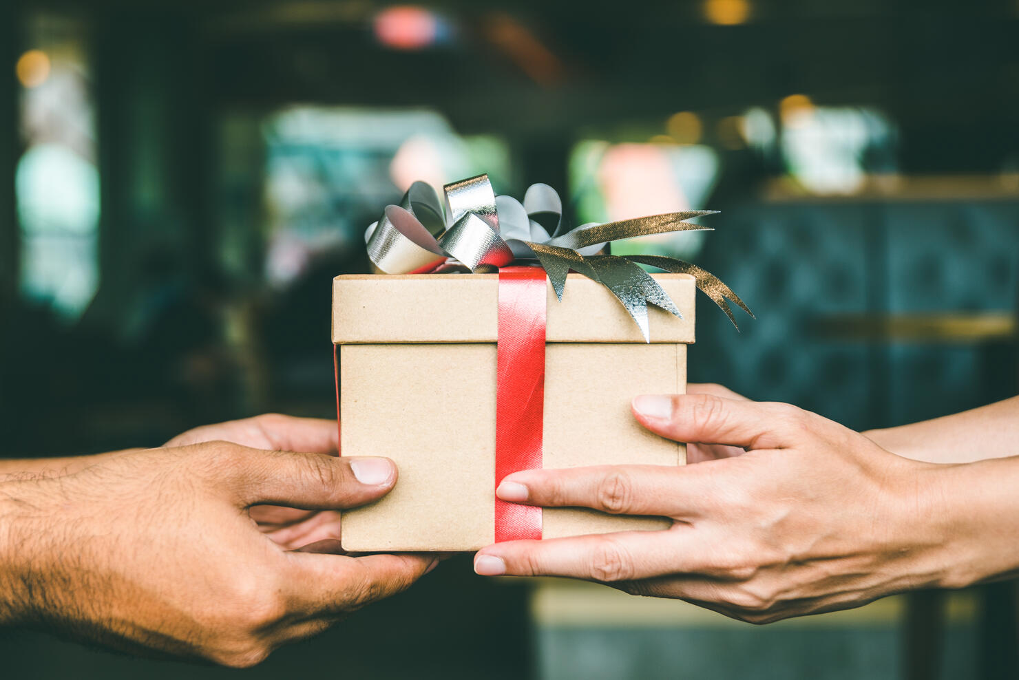 Cropped Hand Of Man Giving Christmas Present To Female Friend