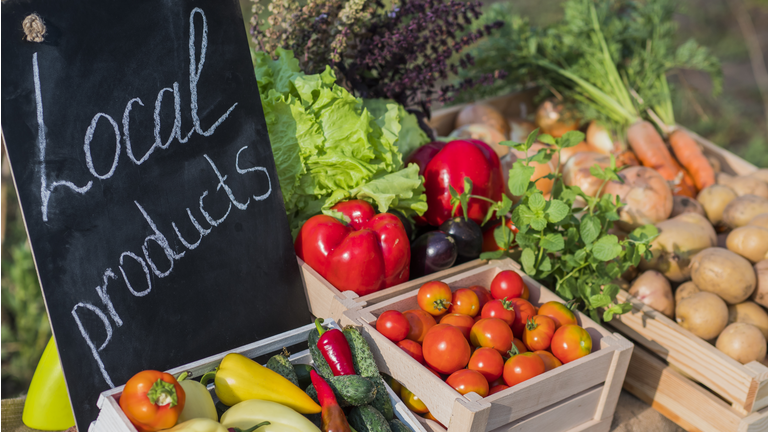 Counter with fresh vegetables and a sign of local products