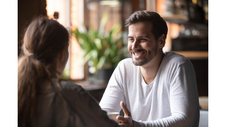 Rear view female sitting at speed dating with smiling man