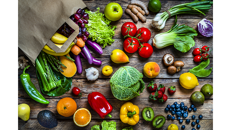 Shopping bag filled with fresh organic fruits and vegetables shot from above on wooden table