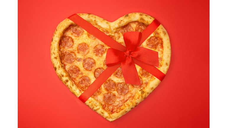 Pizza shaped heart with red bow ribbon for Valentine's Day romantic concept on red background