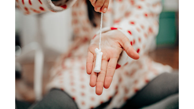 A woman holding one tampon