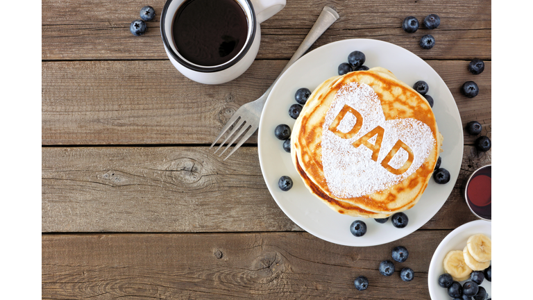 Fathers Day pancake breakfast with heart shape and DAD letters, above view corner border on rustic wood