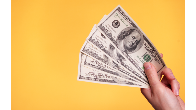 A hand holding five $100 bills