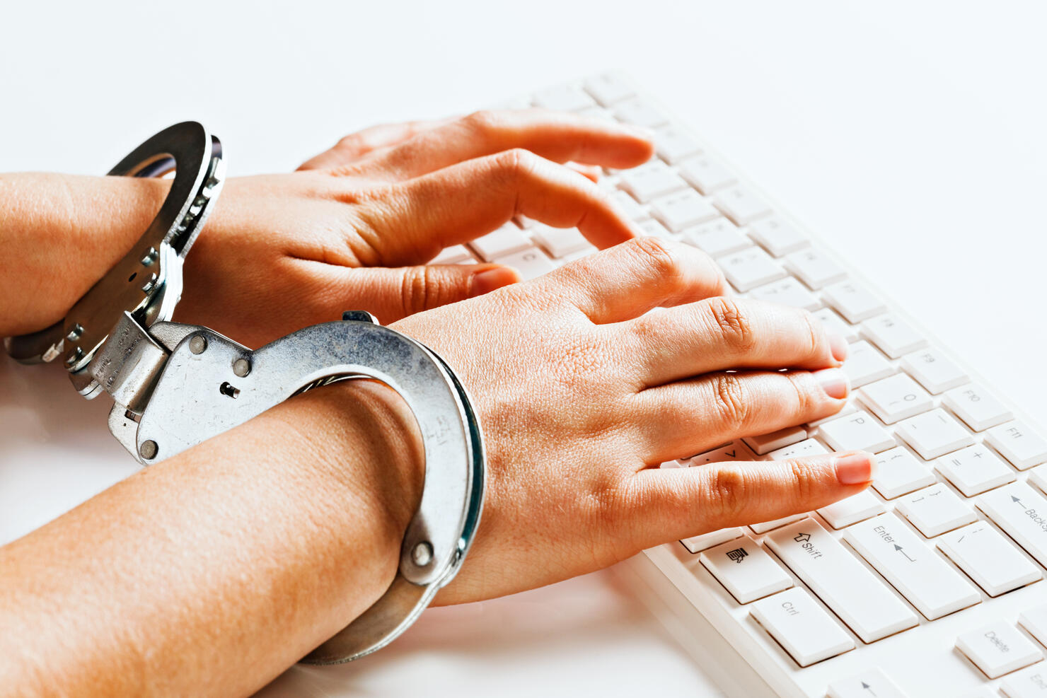 Hands tied unable to write freely on computer in handcuffs