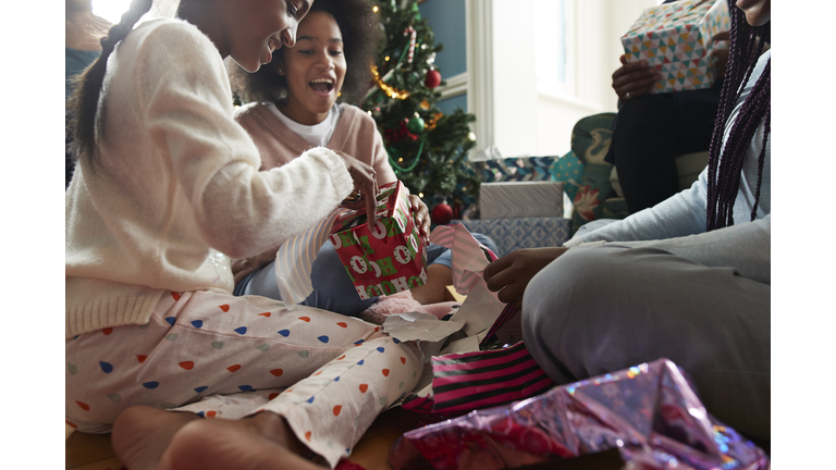 Happy sisters opening Christmas presents at home