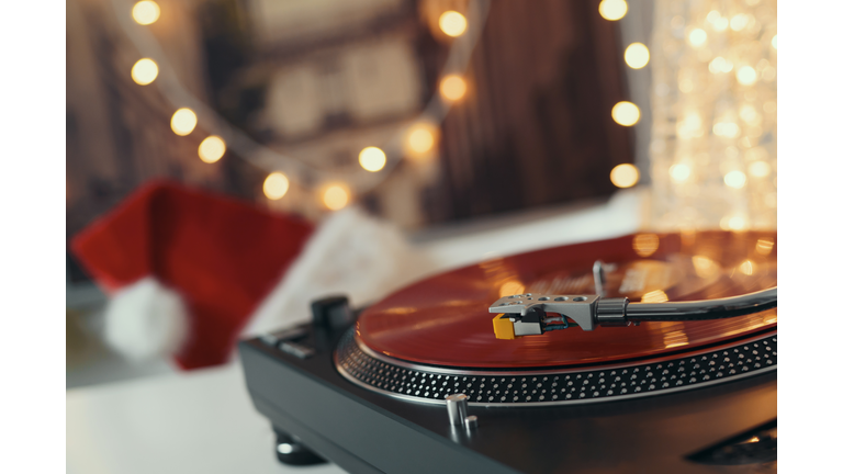 Image of Christmas. Turntable vinyl record player. Sound technology for DJ to mix & play music. Retro audio vinyl record on a background of Christmas decorations