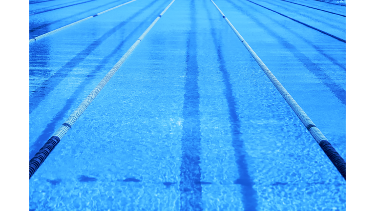 Classic blue Olympic swimming pool with competition lanes. Toned color of the year 2020 trendy blue background.
