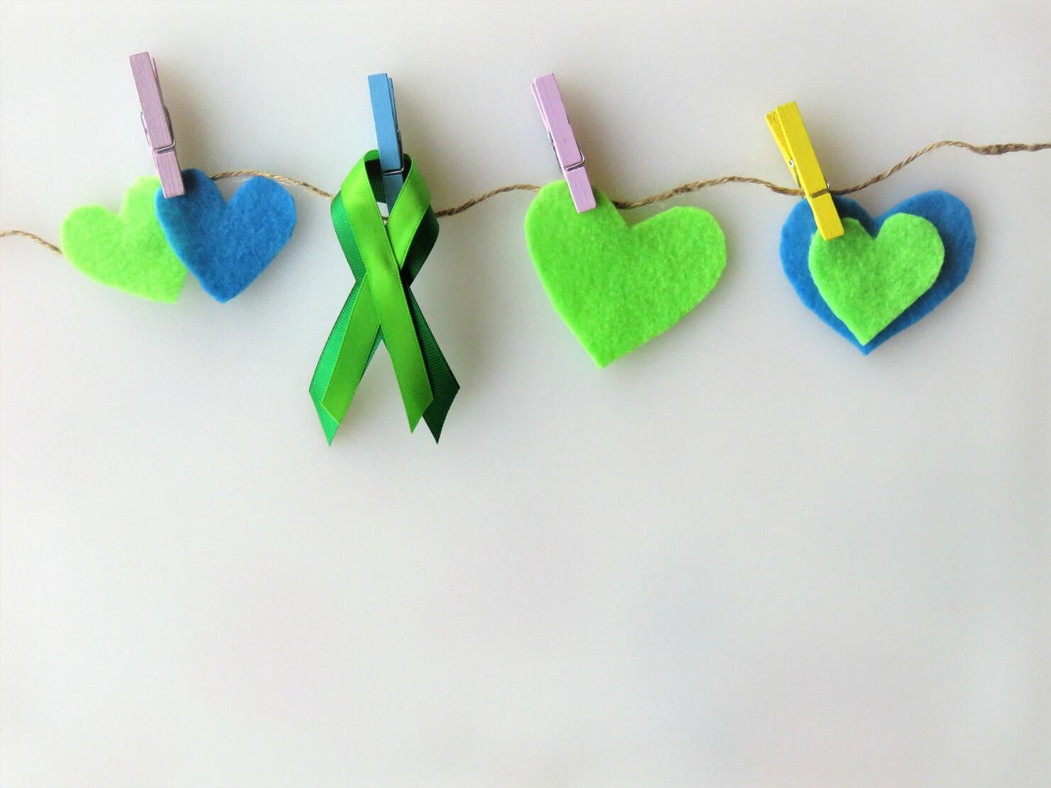 Green ribbon, hearts, pinned to clothesline--Awareness month: Non-Hodgkin lymphoma; mental health