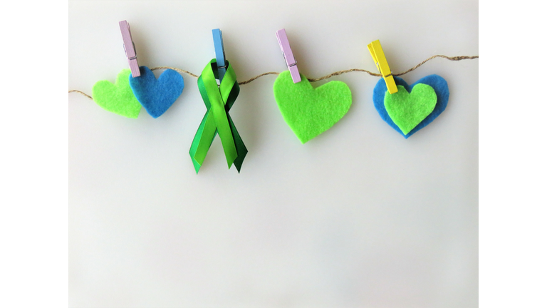 Green ribbon, hearts, pinned to clothesline--Awareness month: Non-Hodgkin lymphoma; mental health