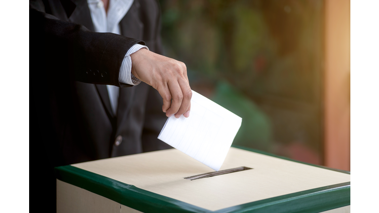 Hand of a person casting a vote into the ballot box during elections