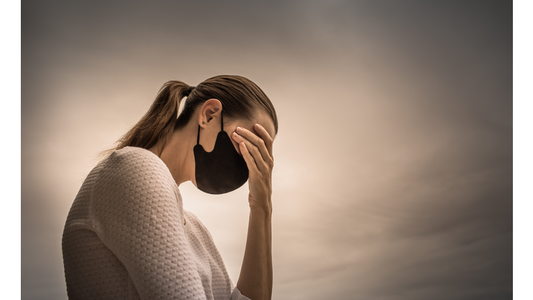 Stressed female wearing protective face mask.