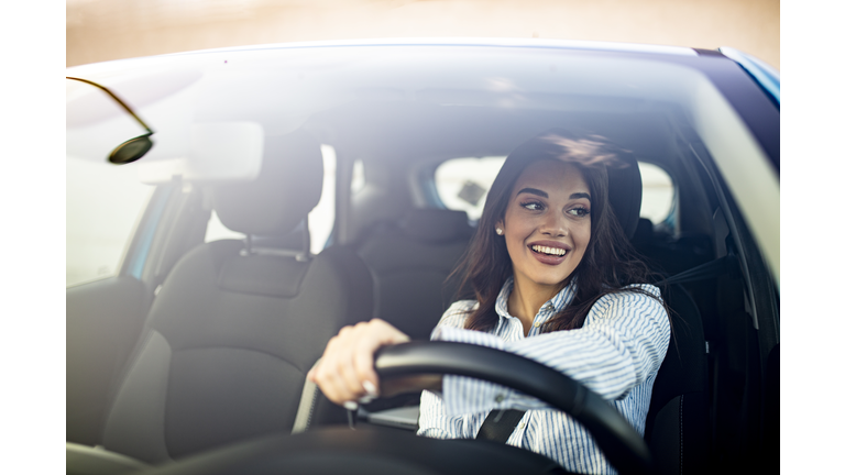 Cute young success happy brunette woman is driving a car.