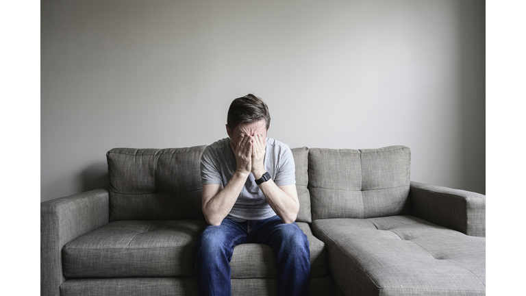 Depressed mature man sitting on couch