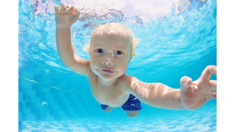 Portrait of baby boy swimming and diving underwater in pool