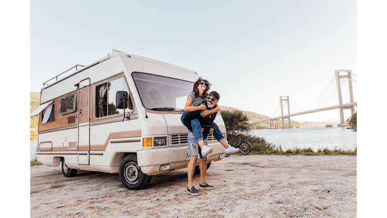 Couple having fun outside of a campervan - stock photo